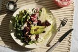 Gebackener Rote-Bete-Salat auf einem Tisch mit Geschirr und Gläsern und einem Brotkorb