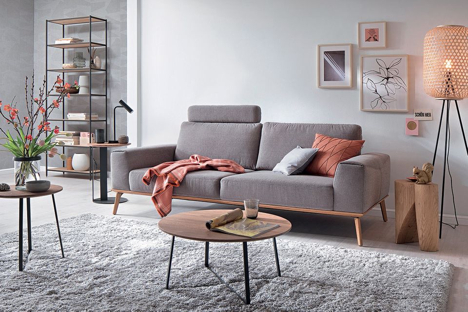 Gemütliches Wohnzimmer mit grauem Sofa und zahlreichen Wohnaccessoires in natürlichen, hellen Tönen