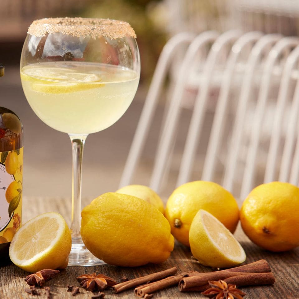 Drink mit Zitronenscheiben und Zimtstangen in einem Glas
