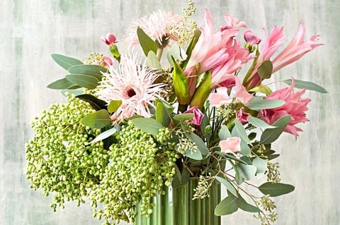 Blumenstrauß mit Nelken, Gerbera und Amarinen und Eucalyptus in grüner Vase auf einem Tisch