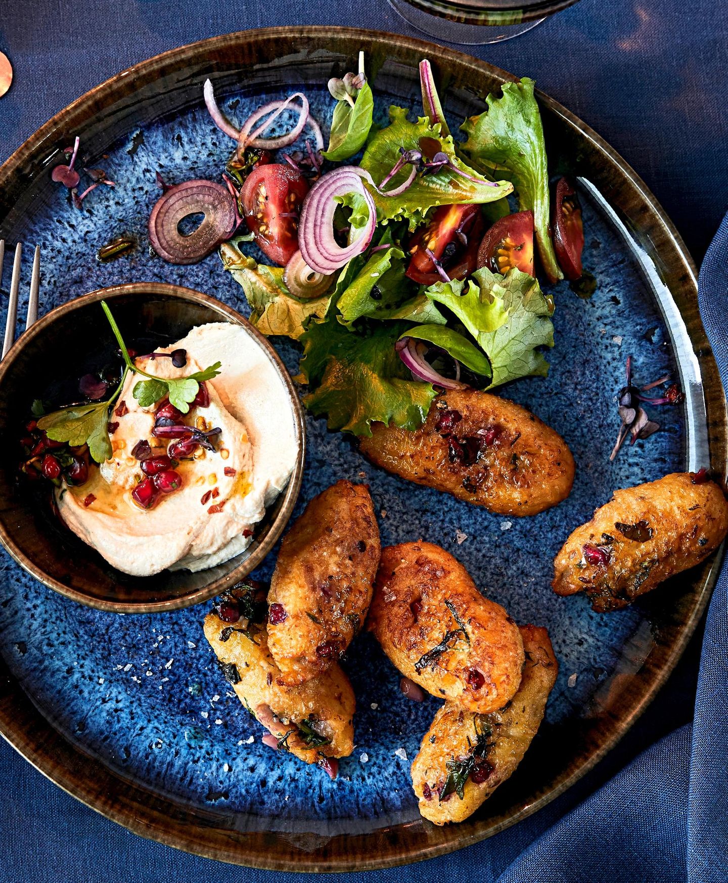 Granatapfel-Kibbeh mit Salat und Dip auf einem blauen Teller