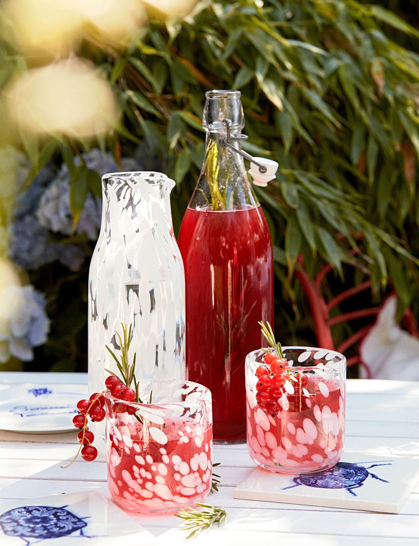 Gläser und Flasche mit rotem Sirup auf einem Tisch