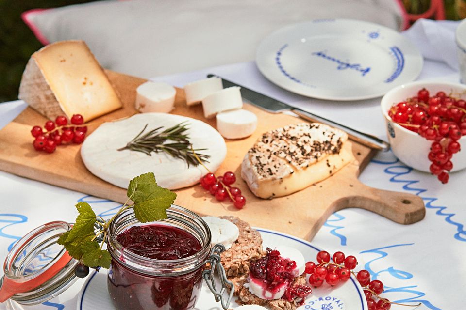 Teller mit Brot, Marmelade und ein Brett mit diversen Käse auf einem Tisch